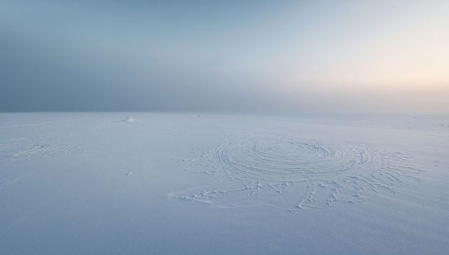 Revealing concentric spiral pattern in packed snow on frozen arctic plain at sunrise