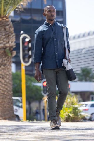 African american man walking downtown wearing navy button-down carrying two-tone satchel