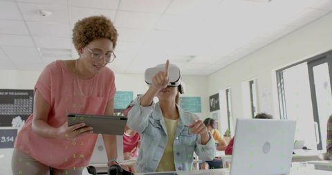 Instructor guiding student using VR headset and tablet in modern collaborative classroom