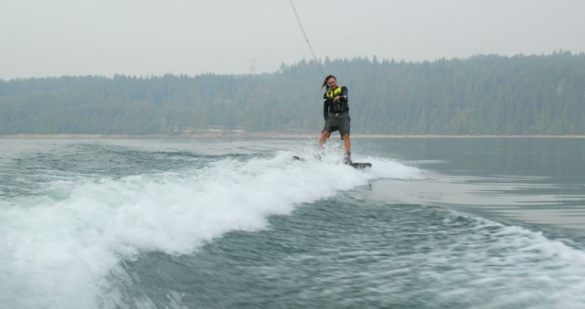 Man Wakeboarding on Calm Lake with Forest Background - Download Free Stock Images Pikwizard.com