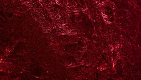 Crimson macro texture showing glossy ridged surface with deep burgundy crevices and sheen