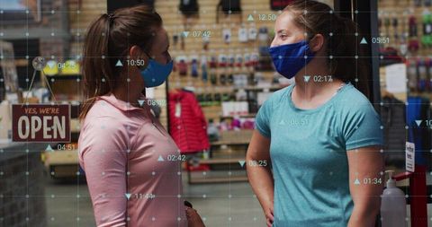 Two Women Wearing Face Masks Chatting in Boutique Shop with Open Sign and Sanitizer