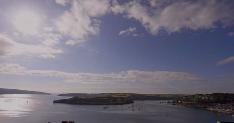 Serene Grassy Peninsula Extending into Tranquil Bay with Moored Boats