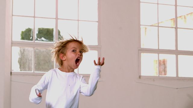 Energetic child in pajamas playing and shouting in a bright room with large windows, emanating joy and freedom. Perfect for illustrating childhood freedom, indoor activities, and family lifestyle in advertising and storytelling.