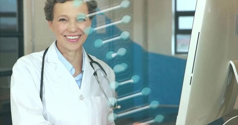 Smiling doctor analyzing data with dna graphic in medical office