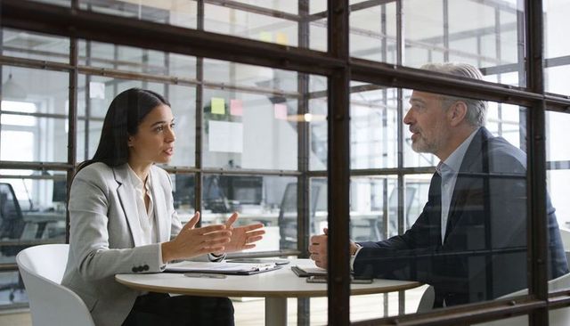 Female executive discussing strategy with senior colleague in modern glass conference room