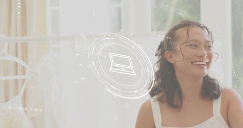 Smiling young woman in white sleeveless top with digital hud laptop icon, bright studio