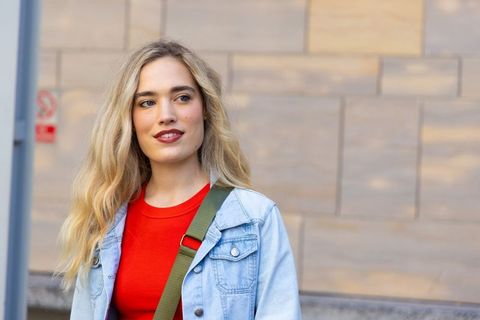 Young woman standing in denim jacket looking right with urban casual style and copy space