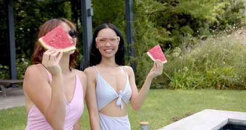 Female friends enjoying watermelon outdoors in summer sun