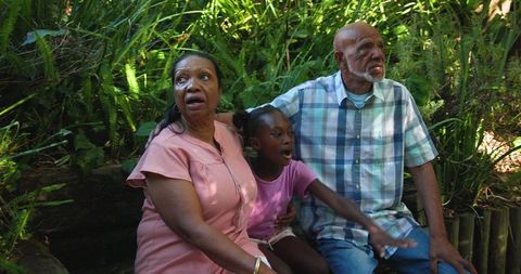 African American Grandparents With Granddaughter Enjoying Garden Life