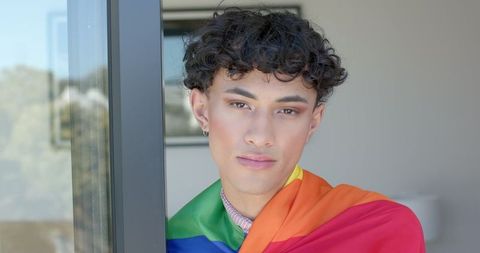 Man Embracing Inclusivity with Rainbow Pride Flag at Modern Home