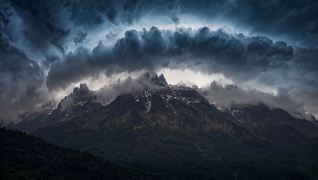 Storm arching over jagged alpine ridge with moody clouds and snow-capped peaks
