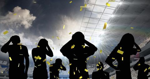 Silhouetted fans disappointed amidst golden confetti at stadium