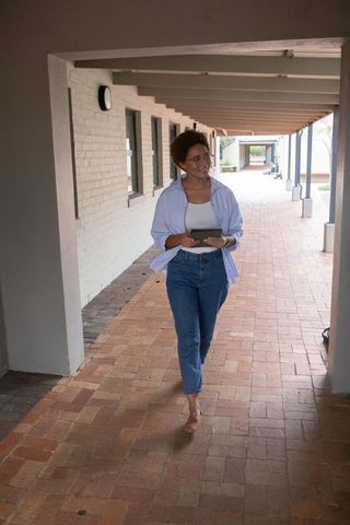 African American Woman Walking in Architectural Corridor with Tablet