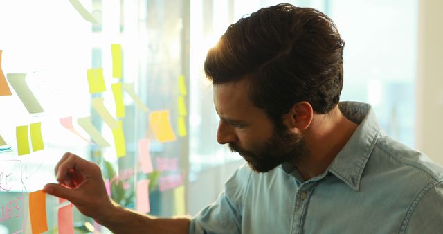 Businessman Brainstorming Ideas on Glass Wall with Sticky Notes - Download Free Stock Images Pikwizard.com