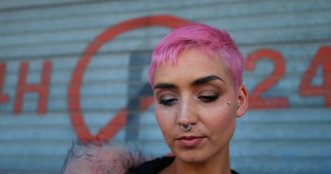 Young woman with pink hair in urban environment
