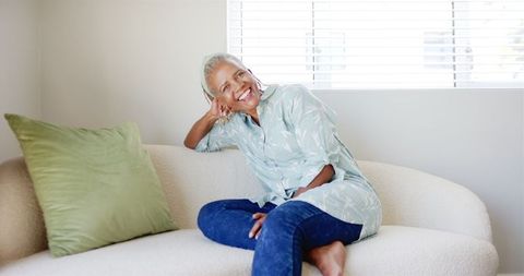 Smiling Senior Woman Relaxing On Modern Sofa At Home