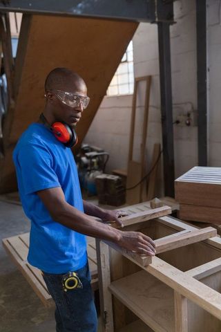 African american carpenter measuring wood frames in workshop, woodworking craftsmanship