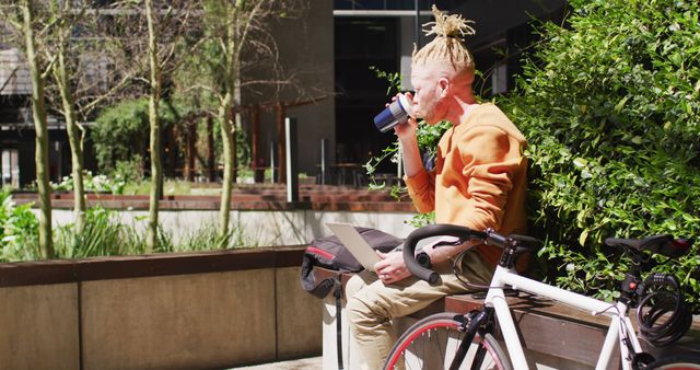 Young man with dreadlocks drinking coffee and using laptop outdoors - Download Free Stock Images Pikwizard.com