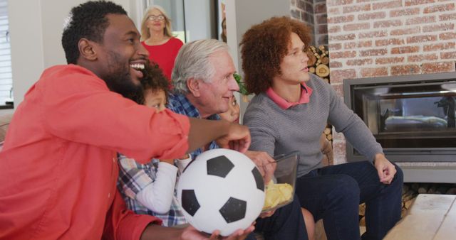 Image of diverse family siting on the couch and watching football match. Family life, spending time together with family.