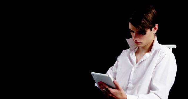 Focused Young Man Reading on Tablet in Dark Background - Download Free Stock Images Pikwizard.com