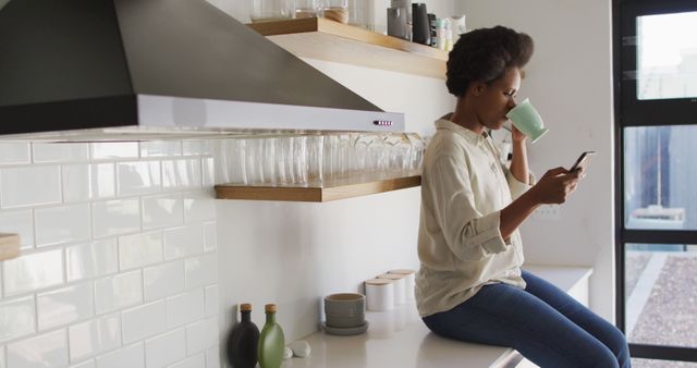 Woman Drinking Coffee and Using Smartphone in Modern Kitchen - Download Free Stock Images Pikwizard.com