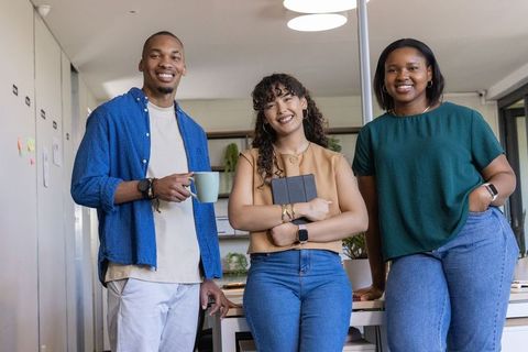 Multicultural young professionals standing and smiling in modern casual office workspace