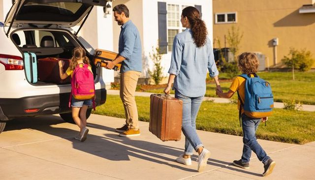 Family loading luggage into suv for road trip on sunny suburban driveway, kids ready