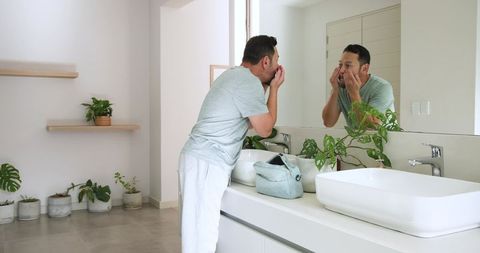 Mature Man Checking Skin in Modern Minimalist Bathroom