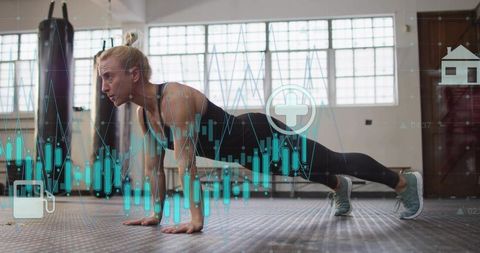 Female athlete holding plank in boxing gym with biometric overlays for fitness tracking