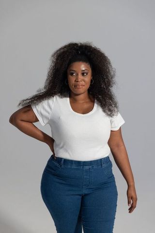 African american woman in midlife posing confidently in white top and blue jeans