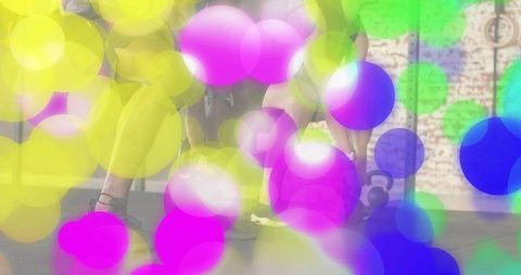 Partners lunging and squatting in gym studio with colorful bokeh and exposed brick wall