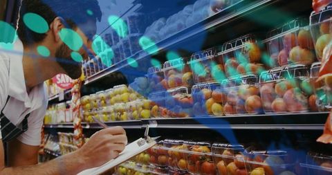 Grocery associate inspecting peach and nectarine inventory with clipboard in produce aisle