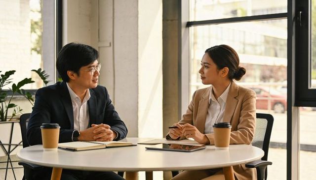 Asian business colleagues discussing strategy over coffee in modern office