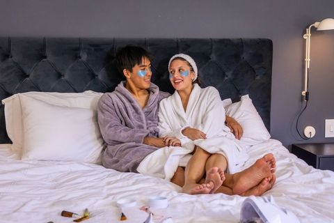 Couple enjoying cozy at-home spa night, relaxing in bathrobes and under-eye patches