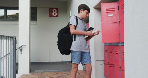 Young student organizing books in school locker area