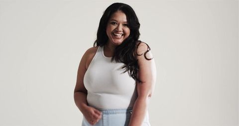 Smiling woman in casual white tank top and denim