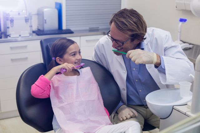 Dentist and young patient brushing teeth together in dental clinic. Ideal for promoting dental care, oral hygiene, pediatric dentistry, and healthcare services. Suitable for use in dental clinic websites, educational materials, and healthcare advertisements.