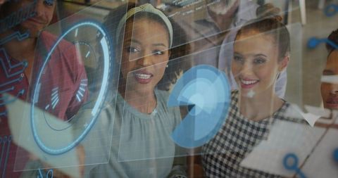 Diverse tech team collaborating around interactive glass display with holographic data visuals