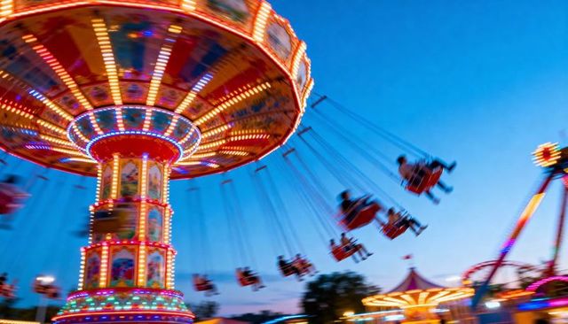Colorful spinning swing ride at dusk with motion blur and glowing carnival lights