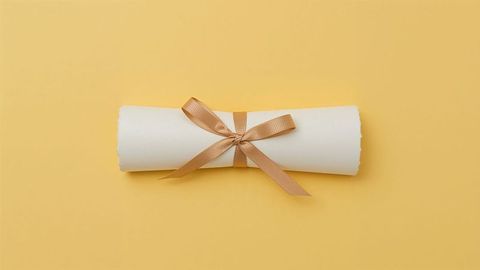 Elegant paper scroll tied with satin ribbon on yellow background