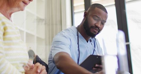 Homecare nurse consulting elderly patient with clipboard providing compassionate medical support