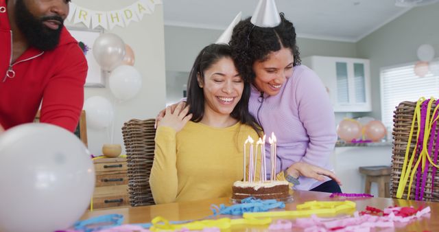 Image of woman blowing out candles on birthday cake celebrating with diverse friends, in slow motion. Celebration, birthday, friendship and tradition concept.