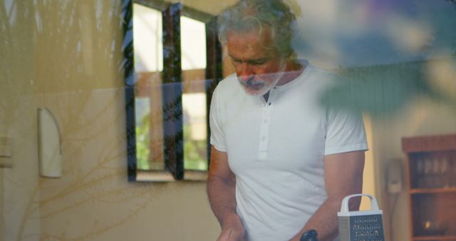 Older Man Preparing Meal in Modern Kitchen Seen Through Window Reflection - Download Free Stock Images Pikwizard.com