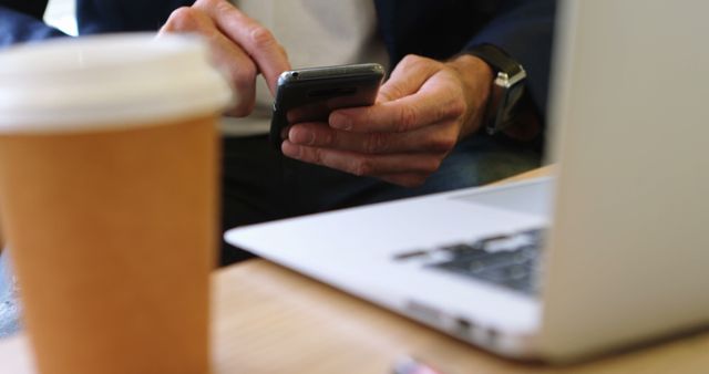 Close-Up of Man Using Smartphone Next to Coffee and Laptop - Download Free Stock Images Pikwizard.com