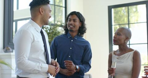 Diverse professionals networking and conversing at modern reception with champagne