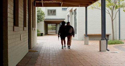 School friends strolling on campus walkway with backpacks