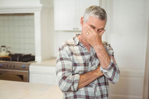 Elderly Man Contemplating in Kitchen Next to Stove