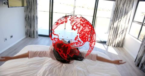 Woman lying on bed with red globe overlay representing global connectivity and remote work