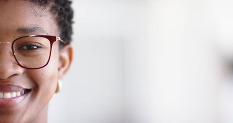 Close-up african american woman smiling wearing burgundy glasses and gold hoop earring